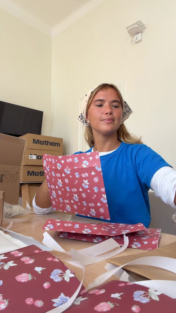 Chica envolviendo producto con papel estampado en el estudio de Djerf Avenue