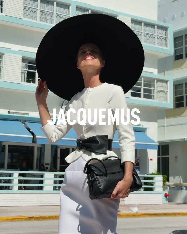 Anuncio de Jacquemus: modelo con un gran sombrero negro y conjunto blanco frente a un edificio de playa