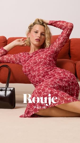 Modelo con vestido rojo estampado sentada en un sofá, campaña de Rouje en casa