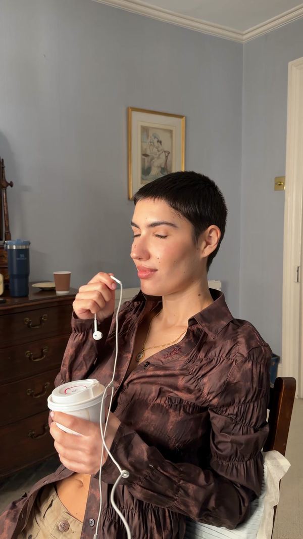 Anuncio de Scuffers: chica con camisa marrón y un café para llevar, foto casera en su casa